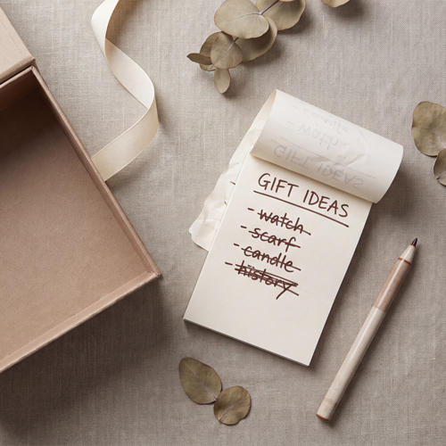 An empty gift box on a linen background along with a notepad