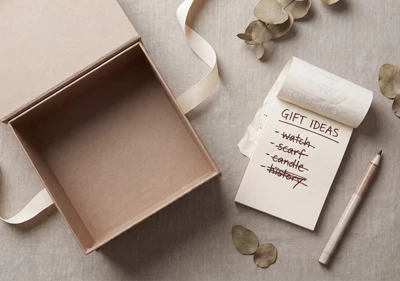An empty gift box on a linen background along with a notepad