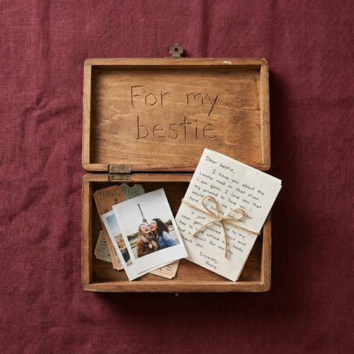 A wooden box with gifts inside on a Linen Background