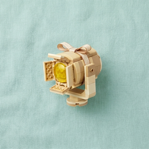 A Spotlight made out of lego inside a gift box on a green linen background