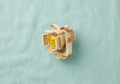 A Spotlight made out of lego inside a gift box on a green linen background