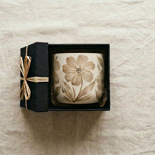 A handpainted pot inside a gift box on a linen background
