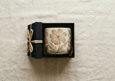 A handpainted pot inside a gift box on a linen background