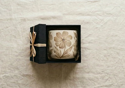 A handpainted pot inside a gift box on a linen background